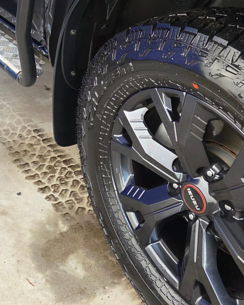 Alloy wheel and all-terrain tyre on a blue ute, cleaned and dressed.