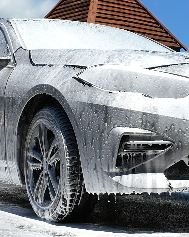 Snow foam dwelling on the flank of a car before the hand wash.