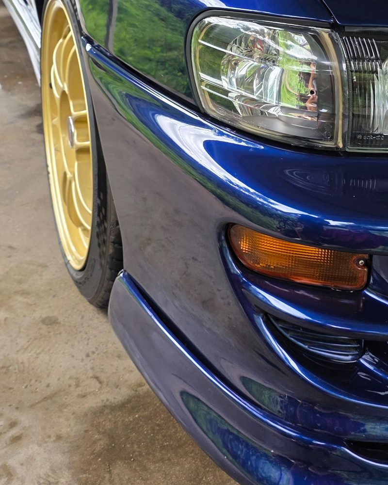 Gold wheel and blue front guard on a Subaru Impreza after polishing.
