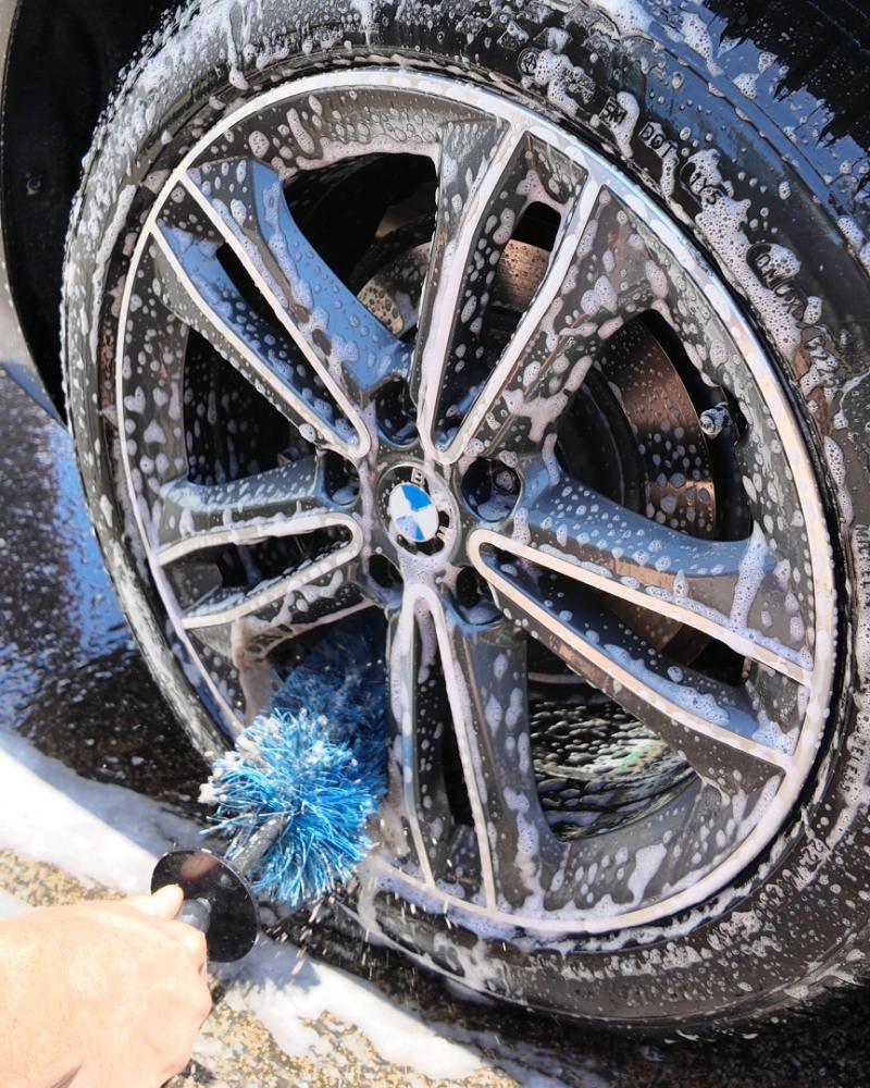 An alloy wheel being cleaned by hand with a soft brush.